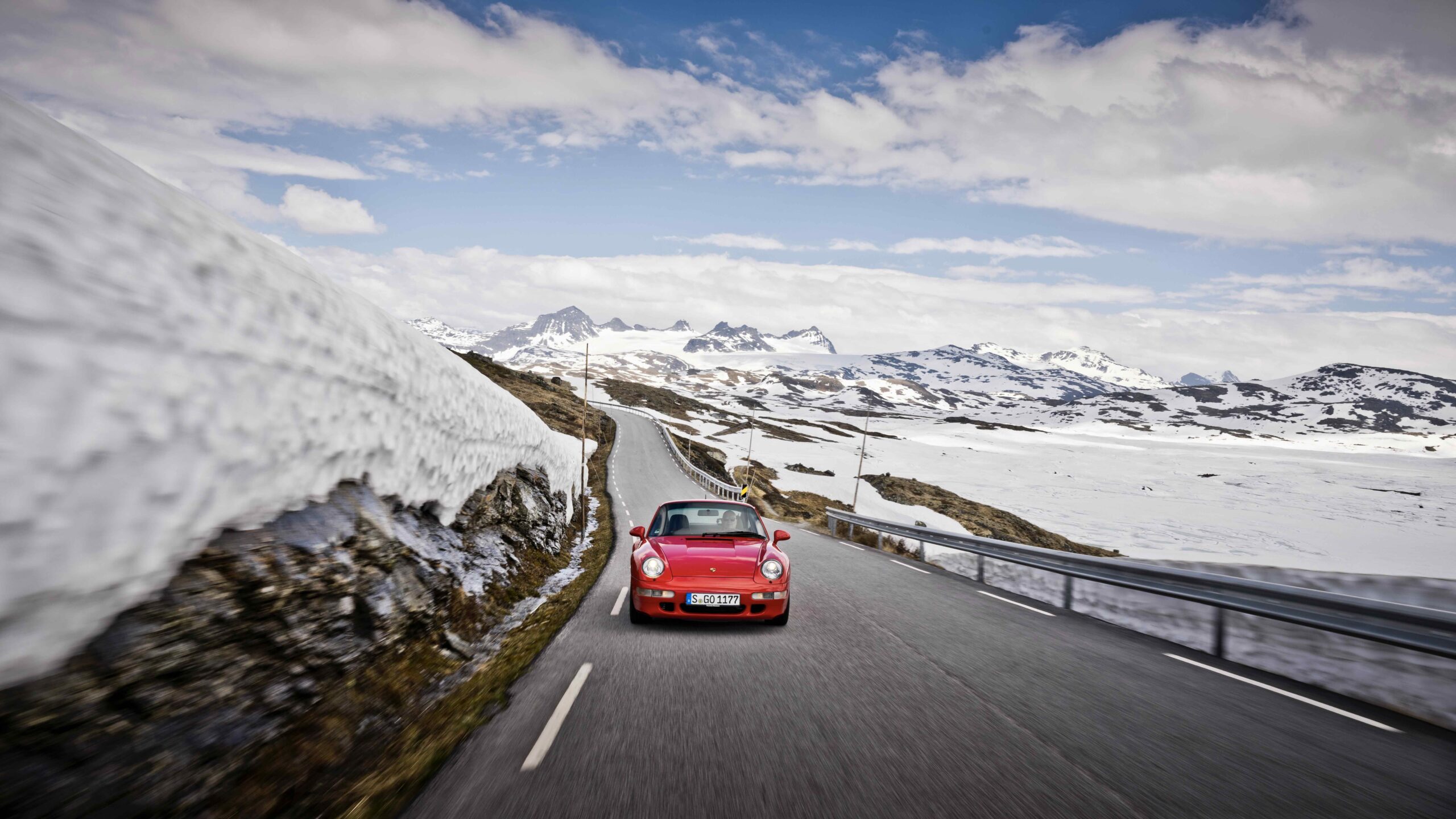Rød bil i norsk fjellandskap.