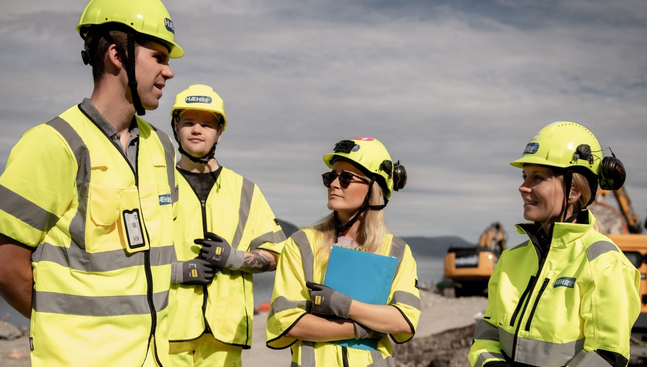 four people at a building site in yellow clothes